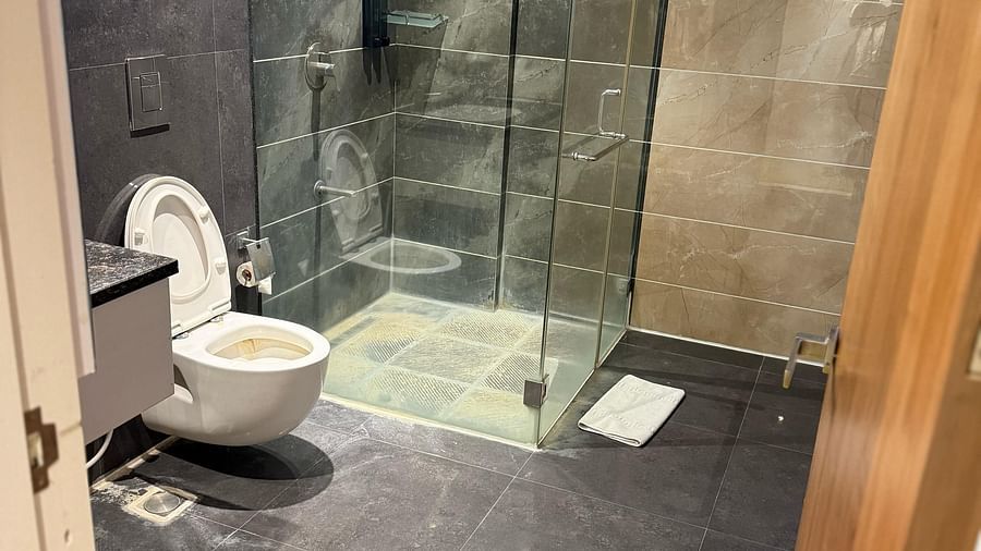 A bathroom at Kyriad Hotel, Gulbarga, featuring a glass-enclosed shower and a toilet.