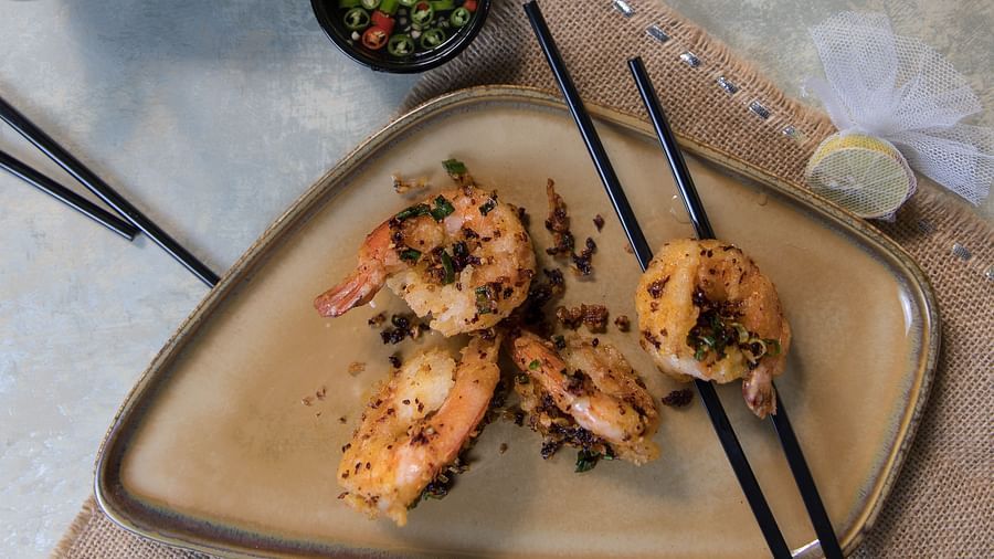 image of a preparation of prawns served with a pair of chopsticks on the plat at the pickwick - The Claridges New Delhi