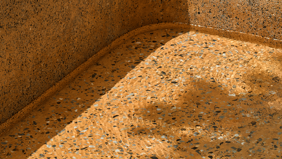 A close-up view featuring the textured interior of an empty stone bathtub at Hotel Sonar Bangla, Ajodhya Hills.