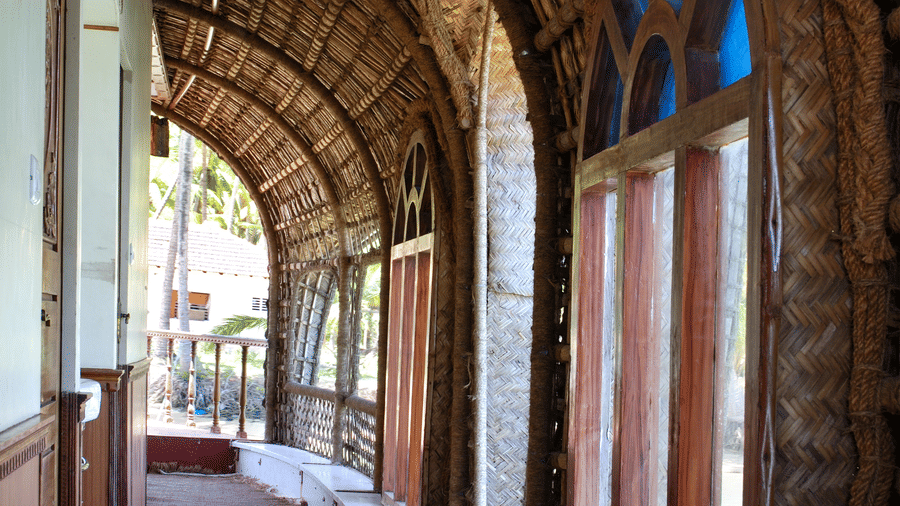 Curved corridor of house boat with arched brick walls, tiled flooring, and an open side with a railing at Paradise Lagoon Resort, Udupi.