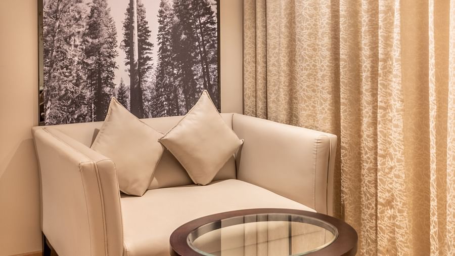 A narrow view of a Superior Room with a bed, a chair, and curtains- TGI Grand Fortuna, Krishnagiri Main Road, Hosur