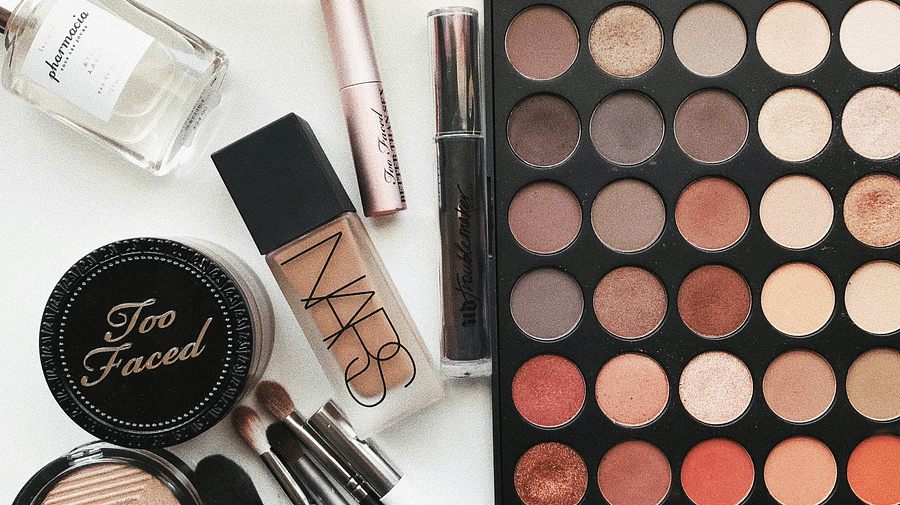 Beauty cosmetic products arranged on a table, featuring brushes and a vibrant color palette