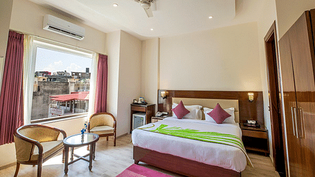 Full view shot of the Deluxe room featuring a double bed along with beautiful city views from the window at Regenta Inn DLS.