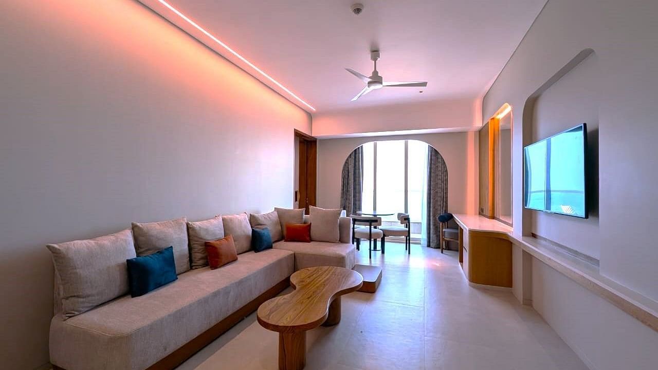 A living area in a suite at Swosti Premium Beach Resorts, Puri, with a couch, table, and television.