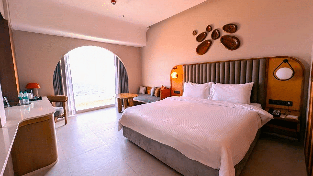 A bedroom at Swosti Premium Beach Resorts, Puri, with a made bed and a decorative wall feature.