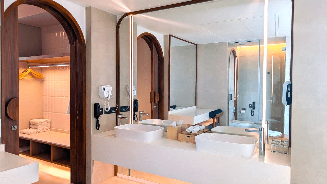 A bathroom at Swosti Premium Beach Resorts, Puri, with a sink, mirror, and decorative lighting.