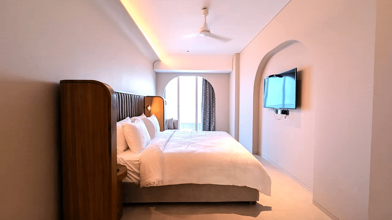 A bedroom at Swosti Premium Beach Resorts, Puri, with a made bed and a television on the wall.