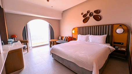 A bedroom at Swosti Premium Beach Resorts, Puri, with a made bed and a decorative wall feature.