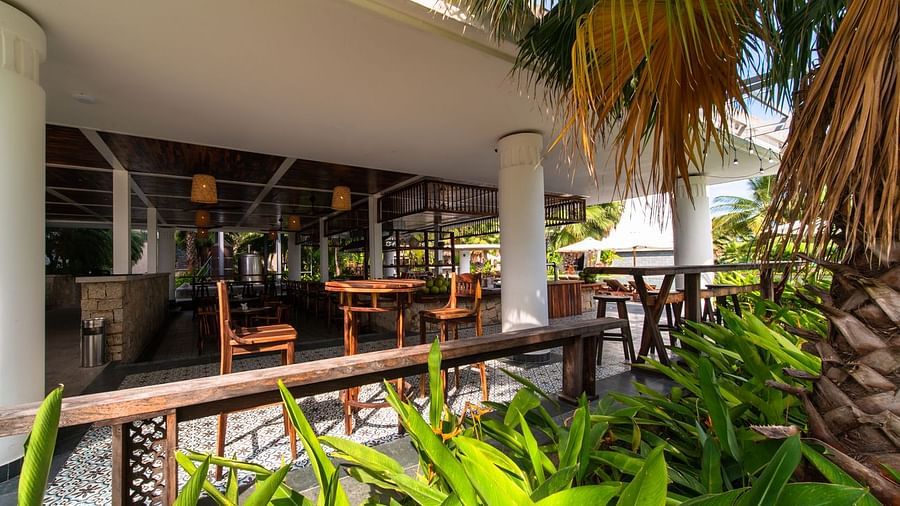 An an outside view of a restaurant that has shrubs and palm trees on the outside - Alibu Resort Nha Thrang