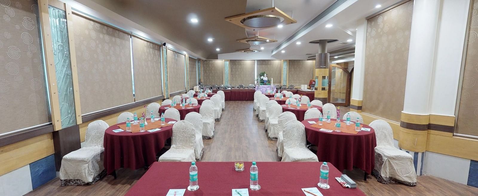 View from the stage of a well lit conference hall setup with designated tables and chairs