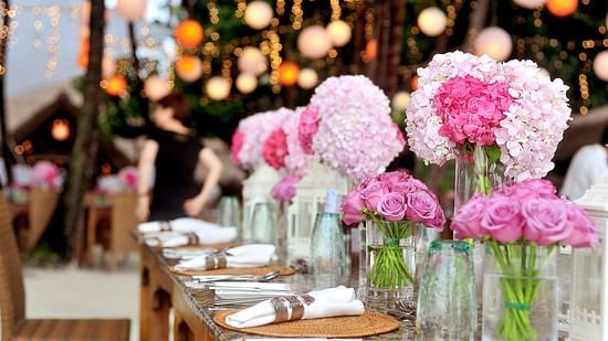 A picture featuring a table set for dining with a lot of flowers on it. 