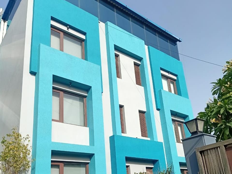 A colourful blue building with multiple windows and some greenery in front - Asian Suites IFFCO Metro, Gurgaon