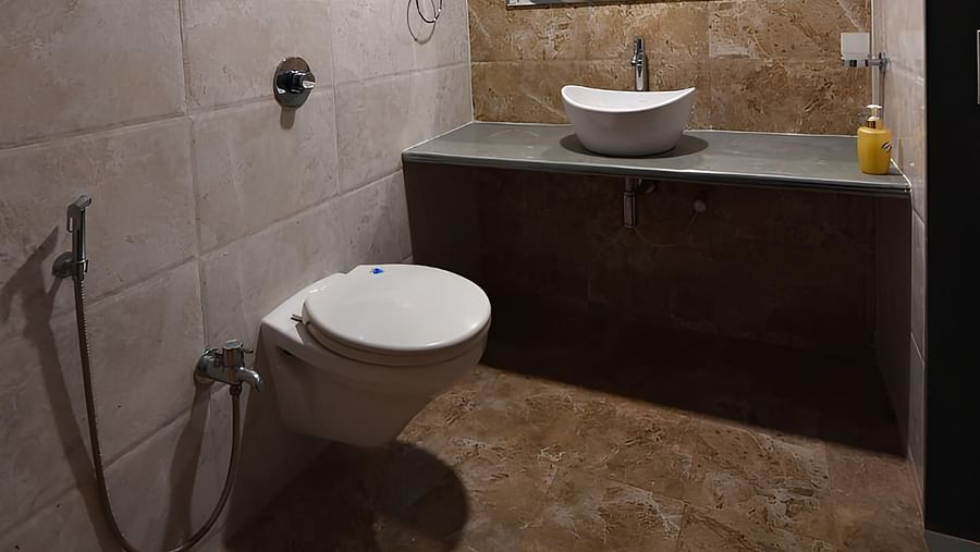 Bathroom of Deluxe Cottage at The Kanila Resort  with a toilet, sink, and vanity with brown cabinets and a marble counter top.