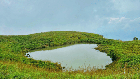The heart shaped lake at Chembra Peak surrounded by grassy slopes.