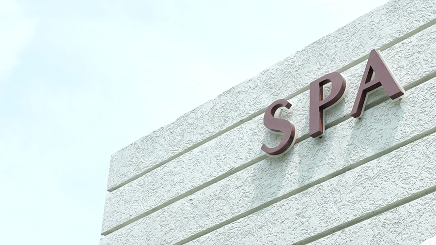 Exterior of a modern building with a minimalist white facade and a sign at the top at Hotel Hukam's Lalit Mahal.