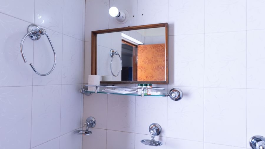 Washroom at Sumitel Premier Inn, Siliguri, featuring a wall mirror, wash basin, modern fittings, and clean white interiors for guest convenience.