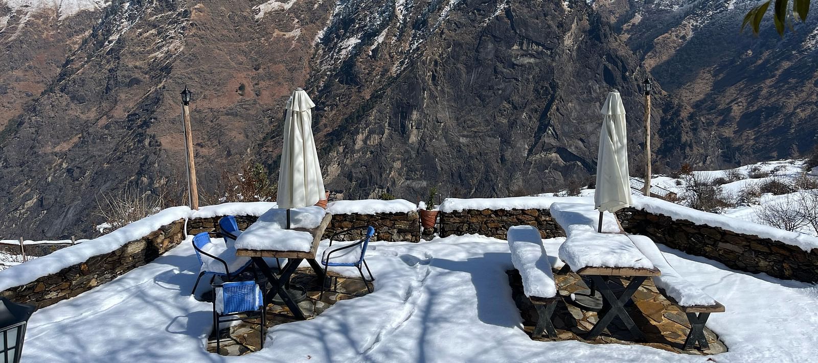 Image of outdoor seating area filled with snow and mountains in the background | Faraway Cottages, Auli