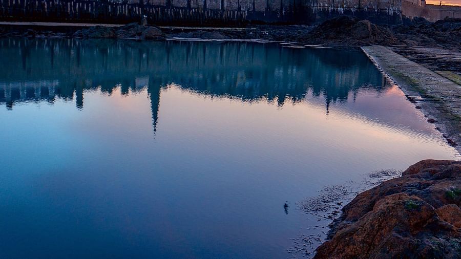 city lake with a building in the background and clouds in different hues during the sun set