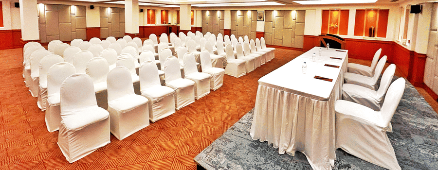 Banquet hall set up in theatre-style seating with white chairs and a head table at The Residency Karur, ideal for conferences and formal gatherings
