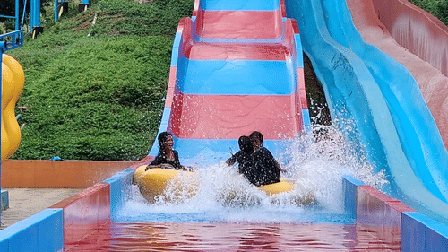 Visitors splashing into the pool on a colorful red-and-blue multi-lane water slide, next to the “Black Thunder” slide at Black Thunder – Water Theme Park.