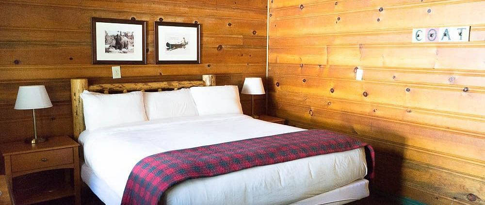 a double bed with a buffalo plaid duvet in a wood-paneled room at Shaver Lake Village Hotel.