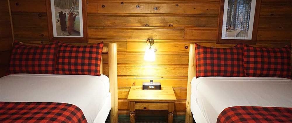A room with twin beds and a side table placed in between them at Shaver Lake Village Hotel.