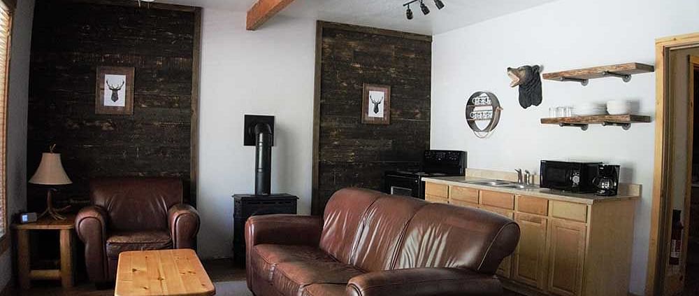 A room at Shaver Lake Village Hotel with a double sofa placed in its center and a wooden coffee table placed in front of it.