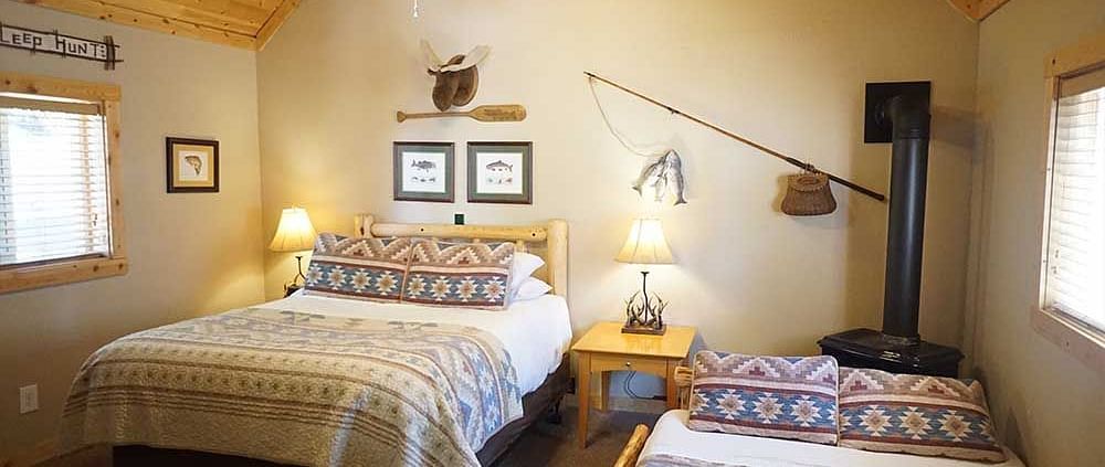 A room with a double bed, side tables, and wooden paneling on the ceiling at Shaver Lake Village Hotel.