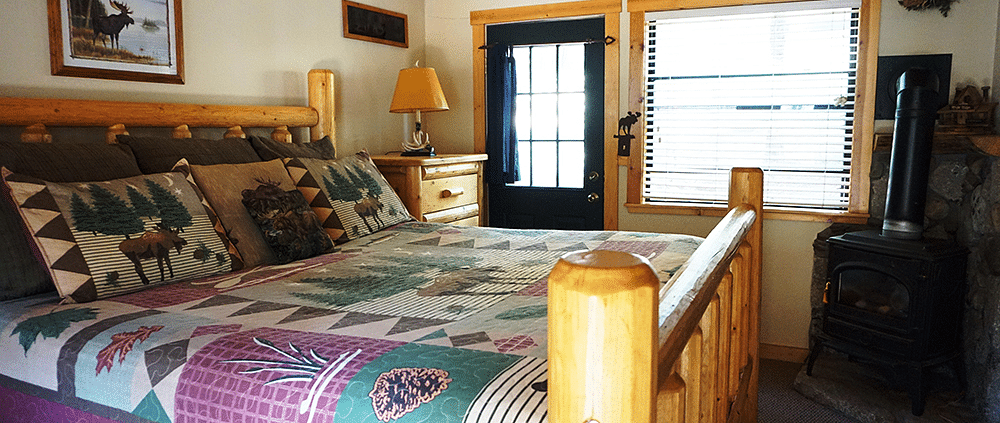 A room with a double bed and wooden paneling on the ceiling at Shaver Lake Village Hotel.