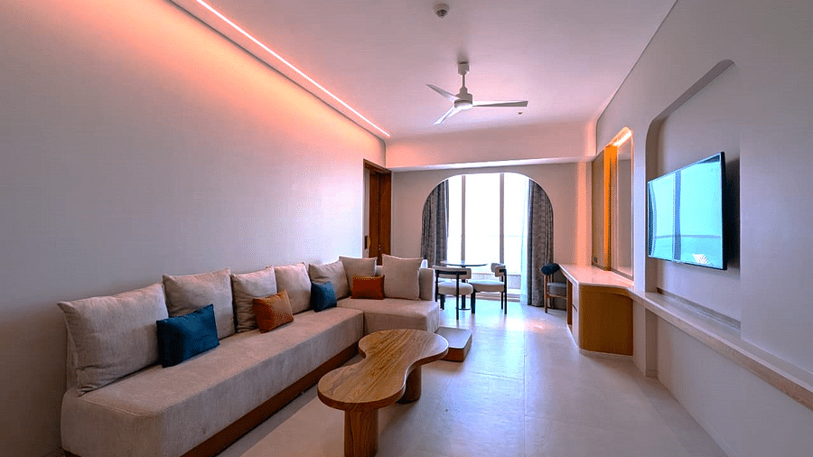 A living area in a suite at Swosti Premium Beach Resorts, Puri, with a couch, table, and television.