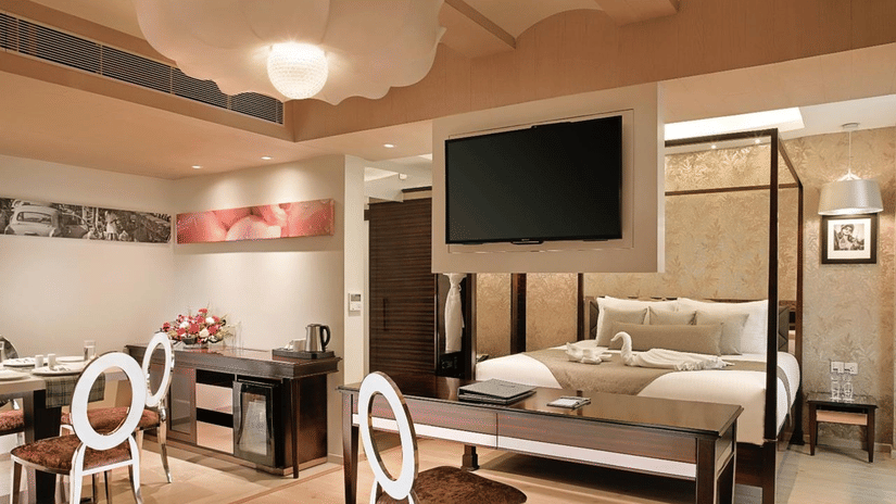 An intricately designed Suite at Barsana Boutique Hotel, Kolkata, featuring a spacious bed, dining space and a work desk.