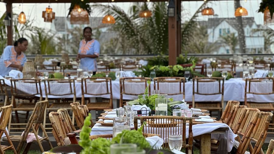 An open dining area featuring several huge dining table paired with wooden chairs. The area is organized for big events like weddings as the tables have bouquets and other decorative elements along with plates and cutlery.
