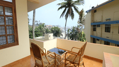 A balcony seating area with chairs and a small table overlooking nearby buildings.
