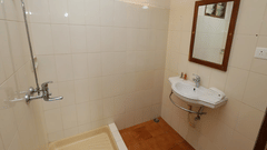 A bathroom in a deluxe room at Abad Serviced Villas, Kovalam with a shower area, washbasin, and mirror.