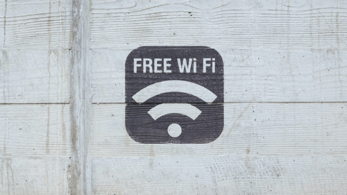 A free Wi-Fi symbol sign is mounted on a concrete wall above a light surface.