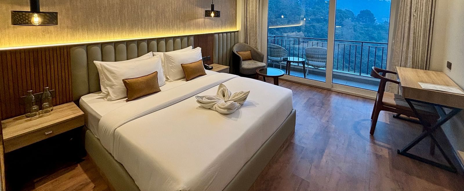 Cosy double bedroom with wooden flooring, ceiling fan, and balcony offering scenic views – ARNISA Boutique Hotel