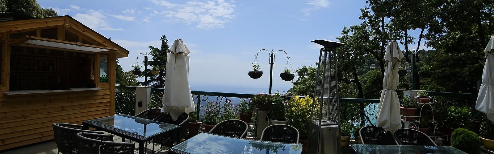 Spacious terrace at Mongas Hotel with multiple dining tables and chairs under clear skies | Mongas Hotel & Resort, Dalhousie 