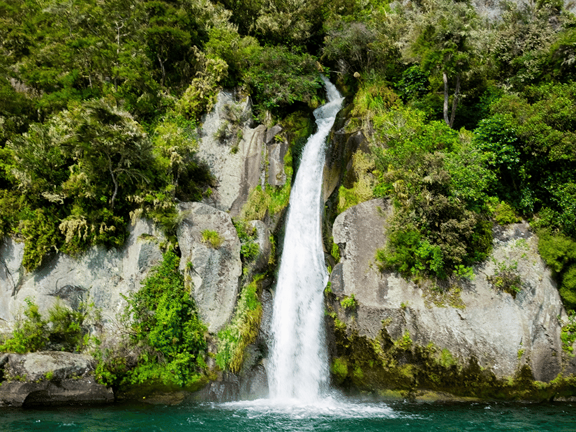 A wide shot of a waterfall, sybolising Kovai Kutralam Falls, surrounded by dense vegetation, it is one of the best Coimbatore visiting places.
