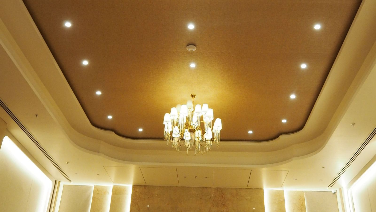 An ornate ceiling with a chandelier in a grand, symmetrical hall - Club Charholi, Pune 