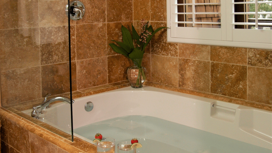 A bathroom featuring a soaking tub and rustic tiles - Brewery Gulch Inn & Spa