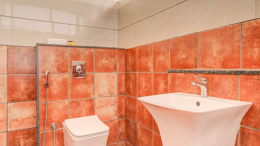 A washroom at Harigovinda's JNStay, featuring a western toilet at the far end and a wash basin to the side