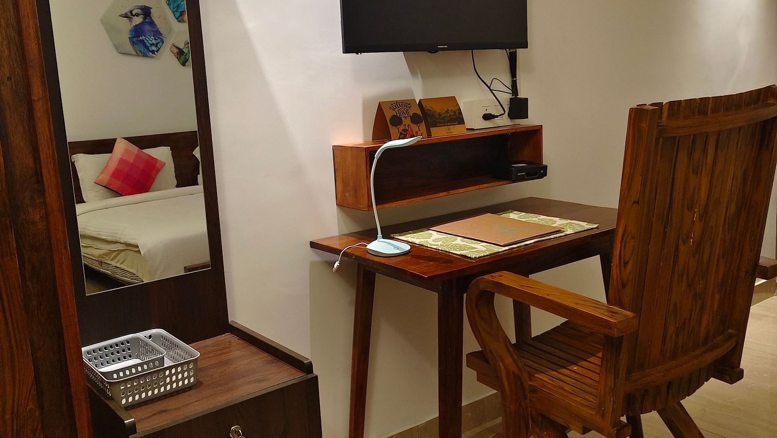 Image of a chair and a study table with a television on the top of it and a small cupboard and a mirror in 101 non-ac room at Ananda Holiday Home, Wayanad 7