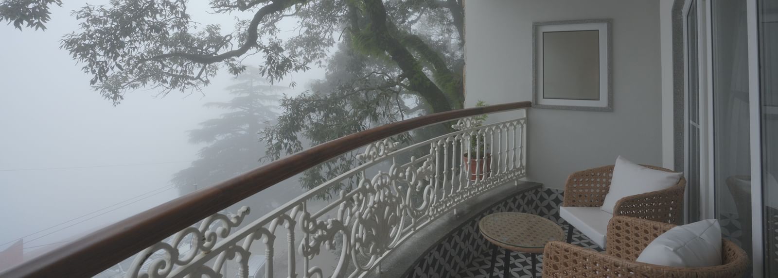 Balcony view overlooking misty trees with elegant outdoor seating - Mayfair Cafe & Suites, Dalhousie
