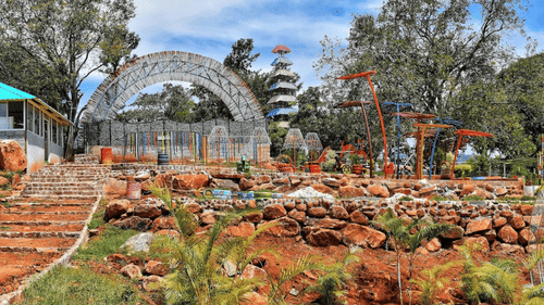 Garden with rocks, plants, and a dome-shaped structure in an outdoor park area.