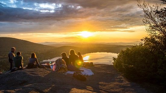 An eventful evening shot of a group of people watching the sunset at a distance on top of a hill