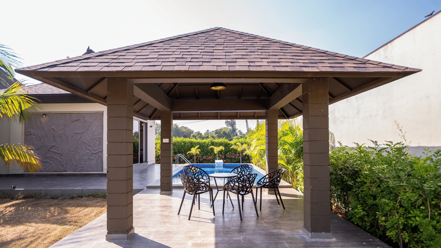 A traditional wooden gazebo with a tiled roof providing a shaded seating area near the pool - Daksh The Nirvana Retreat, Pavagadh
