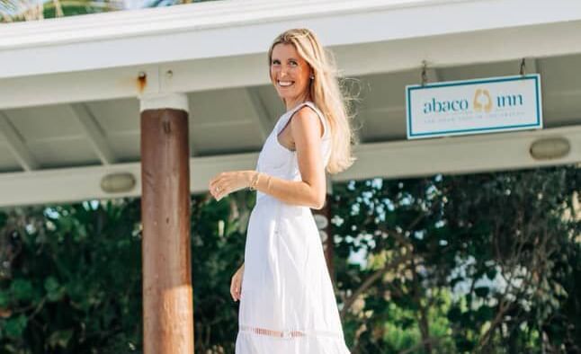Bride in wedding dress stands under a canopy near greenery at Abaco Inn.