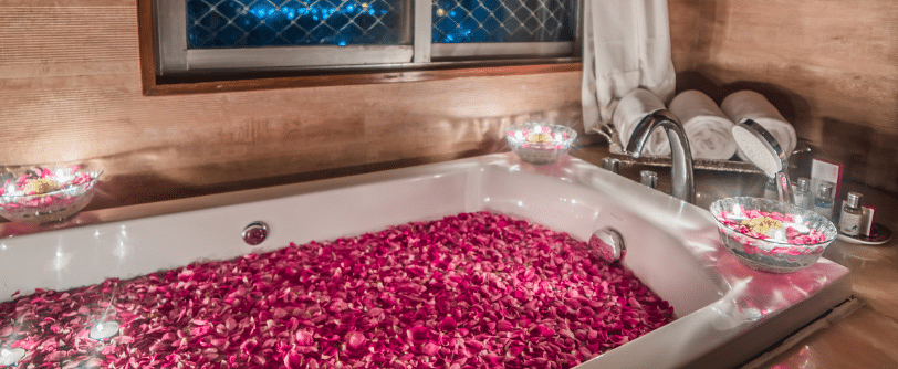 A filled bath tub at Sitara Luxury Hotel in Hyderabad near Ramoji Film City with rose petals and candles around it