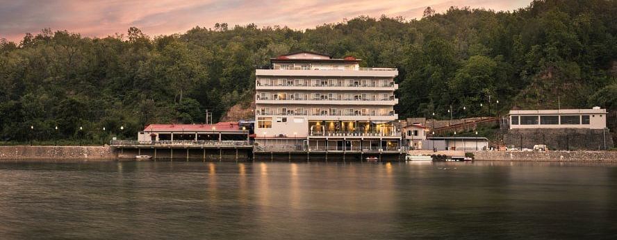 A huge building with a restaurant overlooking a calm lake at sunset.