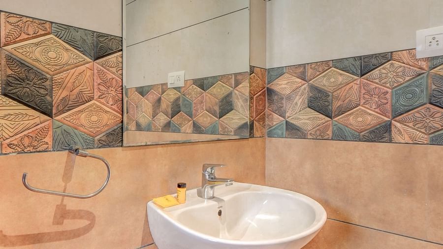 A washroom at Harigovinda's JNStay with a wall-mounted mirror and a washbasin below it